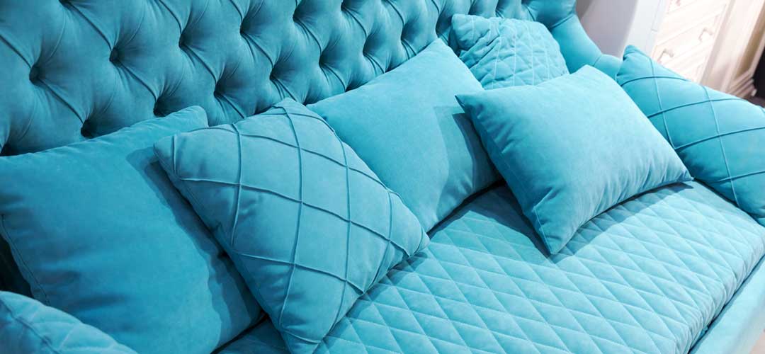 Inviting blue couch with several textures and pillows