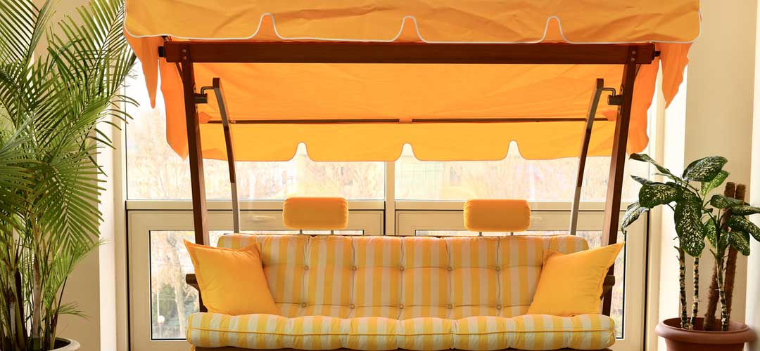 Yellow and white striped swing for outdoor seating with awning