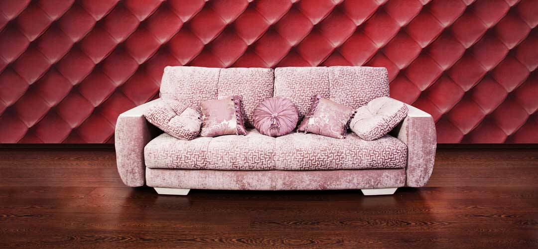 Soft and comfy looking pink couch infront of red diamond tucked wall