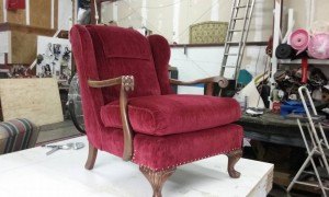 Beautifully restored red chair with wooden legs and arm rests 